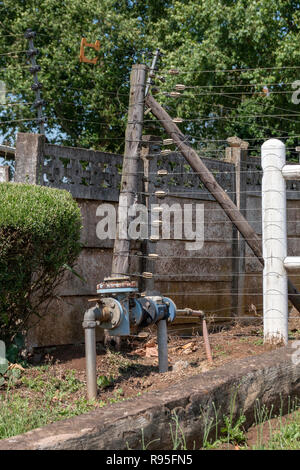 Une vue en gros plan d'une clôture électrique et un compteur d'eau à l'extérieur d'une petite exploitation Banque D'Images