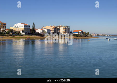 Faro, Portugal. La plage sur le bord de la lagune de Ria Formosa de l'île de Faro, Faro Portugal avec de petits bateaux amarrés et des immeubles d'appartements en arrière-plan Banque D'Images