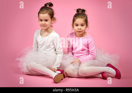 Deux mignonnes petites filles en jupes tulle blanc sur fond rose Banque D'Images