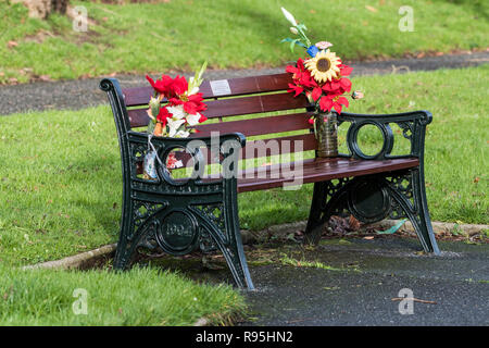 Deux bouquets de fleurs à gauche sur un banc dans un parc commémoratif. Banque D'Images