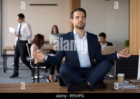 Man in suit sitting on table et méditant dans office Banque D'Images