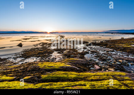 Coucher de soleil à Rimouski, au Québec, du fleuve Saint-Laurent dans la région de la Gaspésie, Canada avec des pierres, rochers, plage de rochers, l'eau turquoise peu profonde, bien au-dessus de la réflexion Banque D'Images