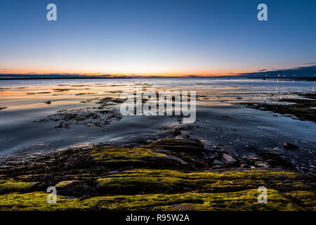 Crépuscule, Crépuscule à Rimouski, au Québec, du fleuve Saint-Laurent, de la Gaspésie, le Canada avec des pierres, rochers, plage de rochers, eau turquoise, soleil reflet seaweed Banque D'Images