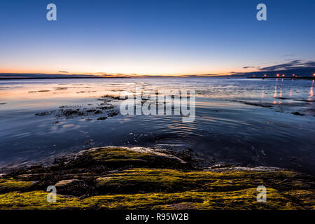 Crépuscule, crépuscule, nuit noire à Rimouski, au Québec, du fleuve Saint-Laurent, de la Gaspésie, le Canada avec des pierres, rochers, plage de rochers, eau turquoise, soleil refléter Banque D'Images