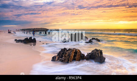 Perth plage au coucher du soleil. Des personnes à l'eau sur un doux soir d'été à Trigg Beach. Perth, Australie occidentale Banque D'Images