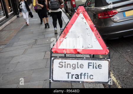 Libre d'un panneau d'avertissement de trafic est visible dans cette image. Le signe est pour trafic de fichier. Les piétons et les voitures sont vues sur l'arrière-plan Banque D'Images