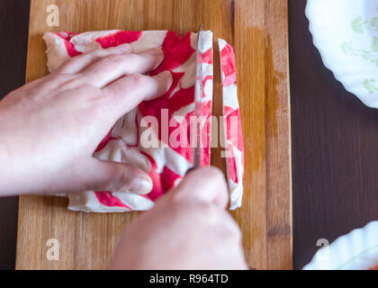 Woman's Hands couper la chair de crabe Kanikama ou Couteau Santoku avec imitation sur une planche à découper en bois. Californie rouleaux de sushi, salades, soupes ou d'une enveloppe en Banque D'Images