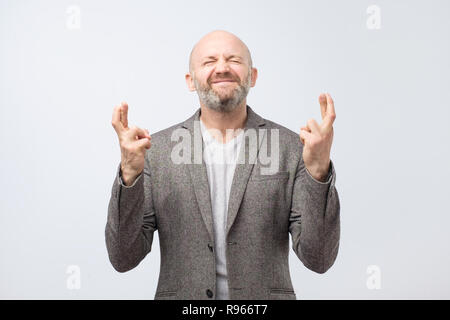 Homme mature optimiste gagner répondre croise les doigts en un souhait. Banque D'Images