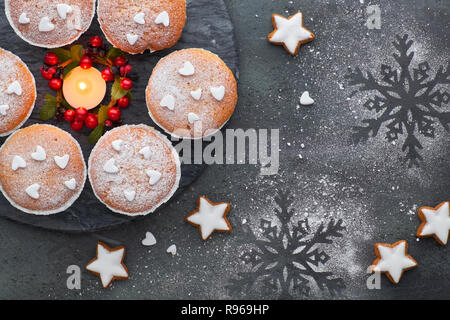 Vue du dessus de la table avec du sucre saupoudré de muffins et biscuits de Noël étoiles sur fond texturé noir Banque D'Images