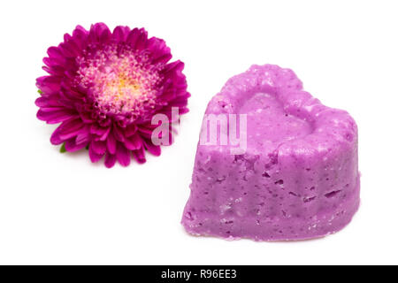 En forme de coeur violet naturel le sel de bain moulé à la main avec fleur cramoisie, isolé sur blanc. Banque D'Images