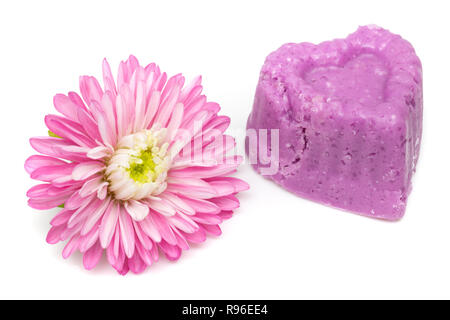 En forme de coeur violet naturel le sel de bain moulé à la main avec fleur rose, isolé. Banque D'Images