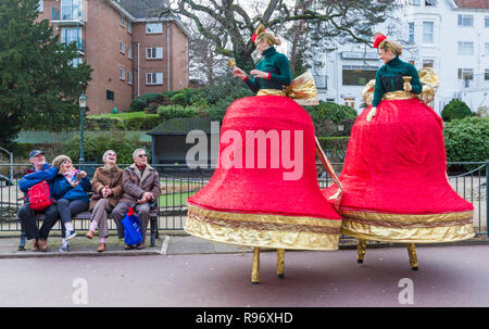 Bournemouth, Dorset, UK. 20 décembre 2018. Ding et Dong, le duo de charme, Noël Belles cloches de Noël sur échasses, errer autour de jardins de Bournemouth rubans chatoyants or et l'écarlate, sonnerie des cloches de Noël de bon temps avec main syncopé chimes. Les femmes personne debout sur des échasses habillés comme des cloches de Noël alors que les aînés s'asseoir sur le banc d'être amusé et rire. Credit : Carolyn Jenkins/Alamy Live News Banque D'Images