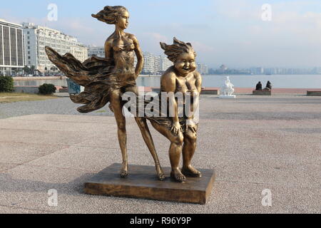 Thessalonique, Grèce. 18Th Oct 2018. Les gens s'asseoir à côté d'une statue de l'artiste chinois Xu Hongfei dans le nord de la ville portuaire grecque de Thessalonique. Quinze statues faites par Xu Hongfei sont exposées au front de mer de Thessalonique entre le 17 décembre et le 24 décembre 2018, dans le cadre de l'exposition de sculptures dans le monde de l'artiste, qui commence à Thessalonique. Crédit photo : Orhan Tsolak / Alamy Live News Banque D'Images