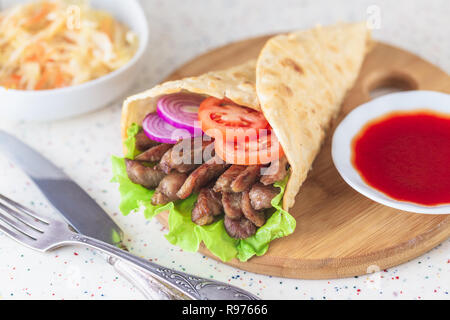 Doner kebab fait main est couchée sur le livre blanc de table en pierre artificielle. Shawarma sur la planche à découper en bois avec la viande de poulet. Banque D'Images