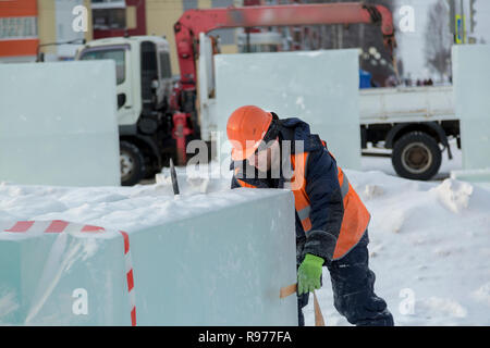 Portrait d'un ajusteur slinger dans un casque et gilet orange sur le déchargement des plaques de glace Banque D'Images