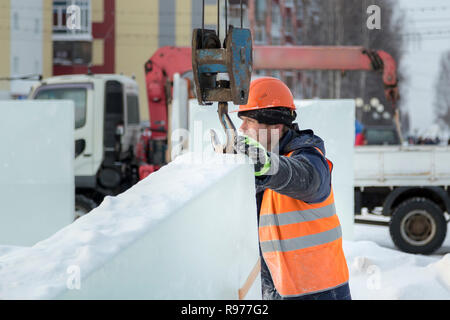 Portrait d'un ajusteur slinger dans un casque et gilet orange sur le déchargement des plaques de glace Banque D'Images