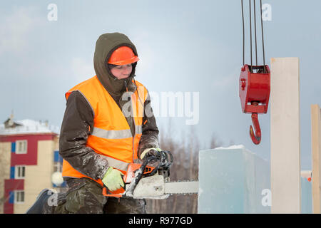 Portrait d'un ajusteur slinger dans un casque et gilet orange sur le déchargement des plaques de glace Banque D'Images