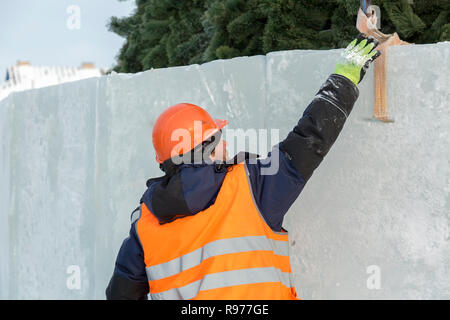 Portrait d'un ajusteur slinger dans un casque et gilet orange sur le déchargement des plaques de glace Banque D'Images