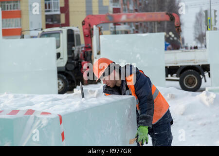 Portrait d'un ajusteur slinger dans un casque et gilet orange sur le déchargement des plaques de glace Banque D'Images