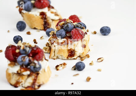 Bruschetta au fromage avec fruits, baies fraîches, noix et un glacis de vinaigre balsamique et la sauce de fruits sur un fond blanc. Banque D'Images