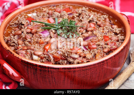 Chili con Carne dans un pot en céramique rouge. Banque D'Images
