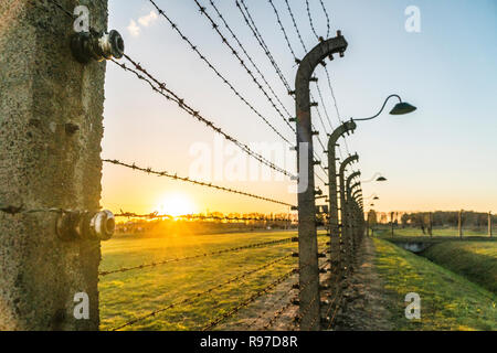 Barbelés entourant le camp de concentration avec les lampes au coucher du soleil à Auschwitz Birkenau, Pologne Banque D'Images