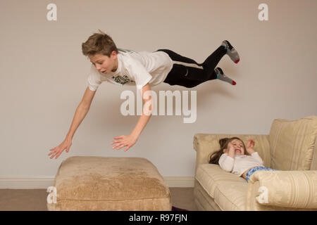 Les enfants, frère et sœur, plongée sous-marine saut et sauter sur les meubles, d'être bruyant et turbulent, hyperactif, pleine d'énergie, à l'intérieur Banque D'Images