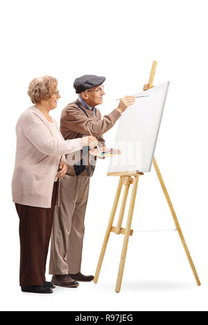 Tourné sur toute la longueur d'un couple de personnes âgées de l'homme et de la femme avec des brosses de peinture sur une toile isolé sur fond blanc Banque D'Images