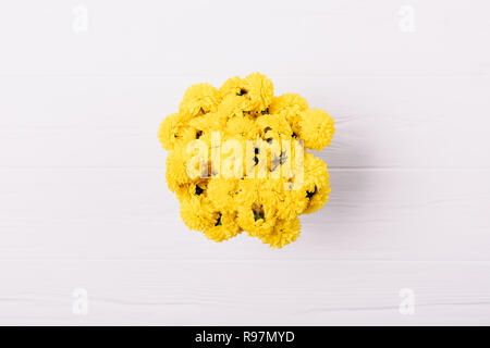 Vue de dessus rond jaune compact blanc bouquet sur fond de bois, d''une télévision. Banque D'Images