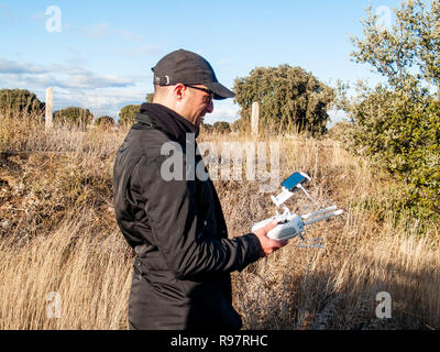 Un pilote de drone piloter avec la télécommande avec le smartphone dans ses mains dans la forêt Banque D'Images