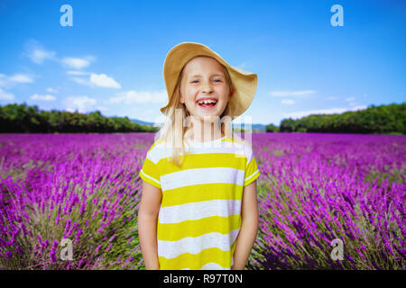 Portrait of smiling enfant en t-shirt jaune et chapeau de paille dans le champ de lavande en Provence, France. Superbe vue sur plateau de Valensole de fleurs de lave Banque D'Images