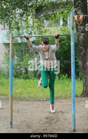 Kovrov, la Russie. 23 juin 2013. Teen girl est engagé dans gimbarr la discipline sur une barre horizontale dans la cour d'un immeuble à plusieurs étages Banque D'Images