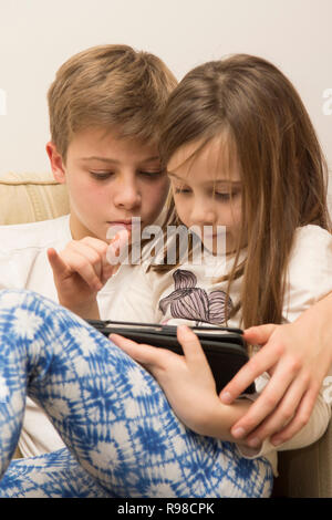 Appareil numérique, tablette, iPad, frère aîné d'aider sœur plus jeune avec les médias sociaux, la technologie moderne Banque D'Images