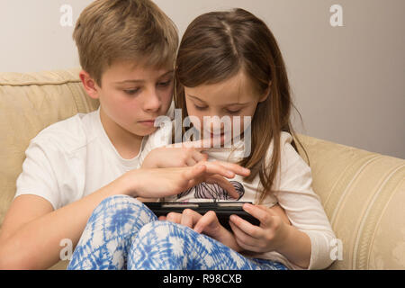 Appareil numérique, tablette, iPad, frère aîné d'aider sœur plus jeune avec les médias sociaux, la technologie moderne Banque D'Images