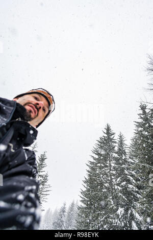 Un homme d'un angle faible avec la neige qui tombe du ciel au-dessus de lui. Banque D'Images