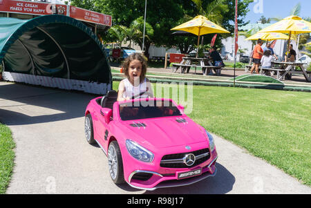 TAURANGA Nouvelle-zélande - Décembre 16,2018 ; petite fille à l'aire de roulage Mercedes rose jouet batterie voiture autour de petite piste. Banque D'Images