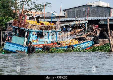 Les hommes très overladen décharger un bateau en bois à Can Tho, Delta du Mékong, Vietnam Banque D'Images