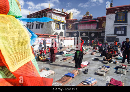 Lhassa, dans la région autonome du Tibet, Chine : pèlerins bouddhistes tibétains postrate et prier par le temple de Jokhang dans quartier du Barkhor. Le Jokhang est considéré comme Banque D'Images