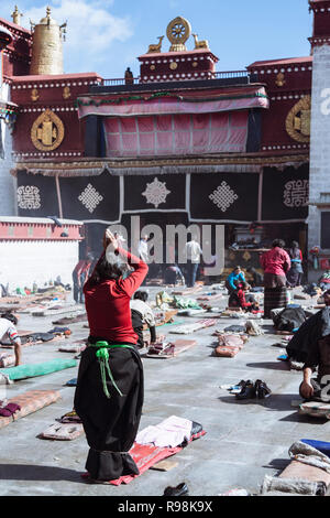 Lhassa, dans la région autonome du Tibet, Chine : pèlerins bouddhistes tibétains postrate et prier par le temple de Jokhang dans quartier du Barkhor. Le Jokhang est considéré comme Banque D'Images