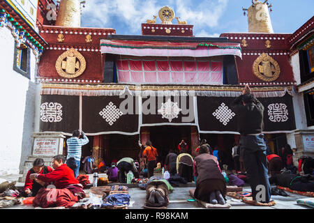 Lhassa, dans la région autonome du Tibet, Chine : pèlerins bouddhistes tibétains postrate et prier par le temple de Jokhang dans quartier du Barkhor. Le Jokhang est considéré comme Banque D'Images