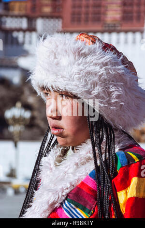 Lhassa, dans la région autonome du Tibet, Chine : Portrait de jeune femme en costume traditionnel tibétain à côté de palais du Potala. Construit en 1645 par le 5ème D Banque D'Images