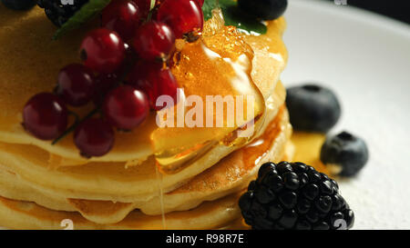 Pile de crêpes maison ou des crêpes décoré sur le dessus avec des baies sauvages - rouge cassis, de mûre et de bleuet. Délicieux et sain petit-déjeuner américain classique. Close-up. Banque D'Images