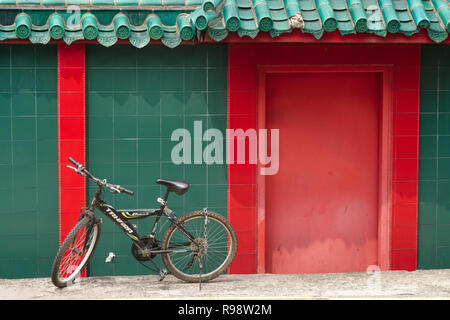 Un vélo garé en face d'un temple chinois dans la zone de Geylang, Singapour Banque D'Images