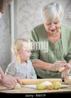 Bénéficiant d'une vieille femme faisant peu de tartes aux pommes avec sa petite-fille. Banque D'Images