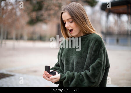 Belle jeune femme en costume élégant à la recherche à l'anneau de mariage dans la région de fort en se tenant sur le flou Banque D'Images