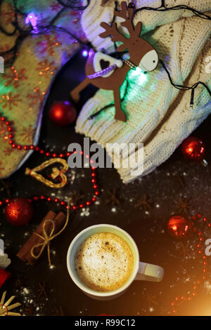 Noël arrière-plan avec des cerfs jouet, café, cannelle, des perles rouges et des jouets sur le tableau noir. Célébration de Noël, vacances, hiver, concepts. Banque D'Images