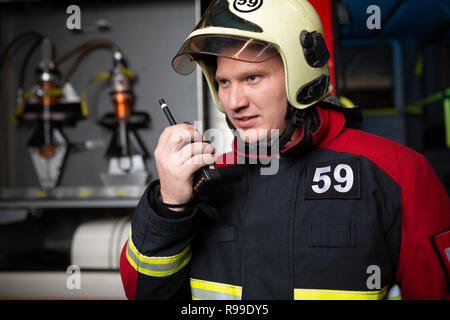 Photo de femme pompier casque en parlant à la radio aux fire station Banque D'Images