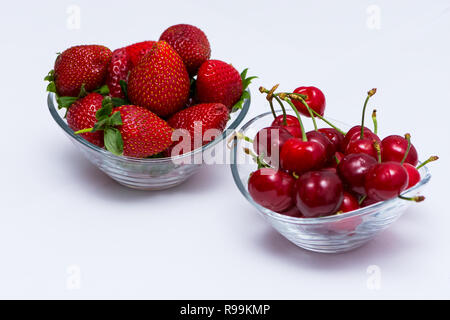 Un bol en verre plein de cerise et un bol plein de fraises sur la table Banque D'Images