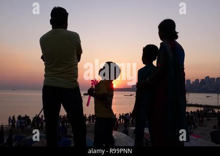 Une famille nucléaire à Mumbai, Inde, dont deux enfants, pour le coucher du soleil à Marine Drive, un boulevard bordant la mer d'Oman Banque D'Images