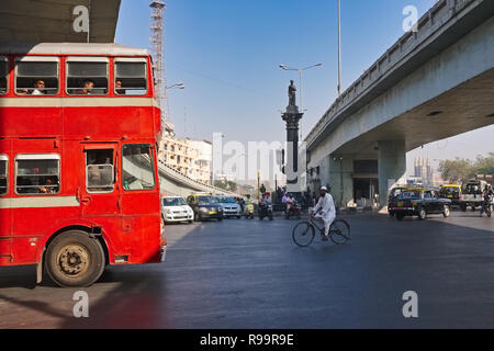Dans un grand carrefour dans Byculla, Mumbai, Inde, un cycliste doit faire face à un large red London-style double-decker bus, géré par la compagnie de bus MIEUX Banque D'Images